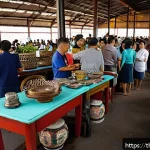 경매사 경력을 활용한 창업 아이디어 - A detailed scene of a vibrant Thai auction market specializing in second-hand goods, featuring diver...